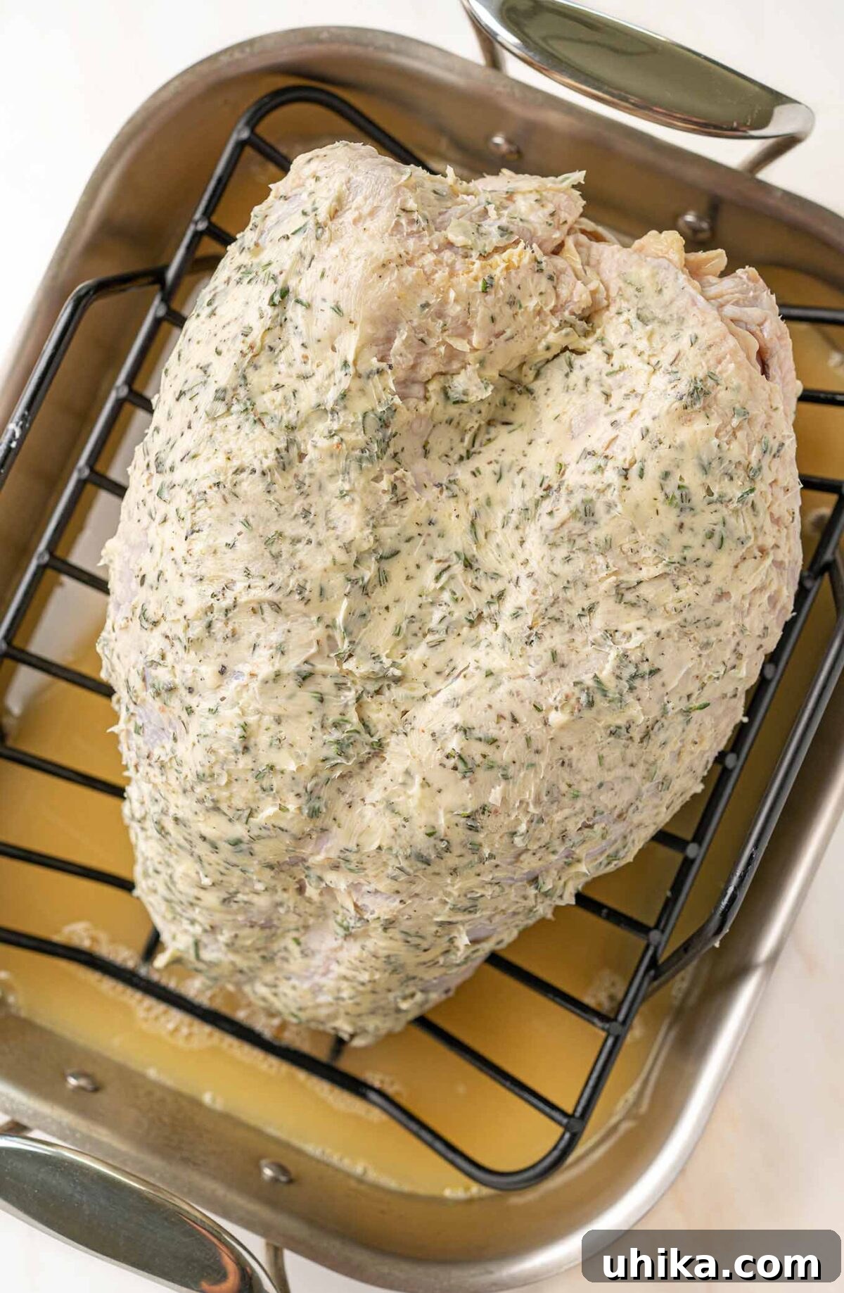 Sweet & Savory Apple Cider Turkey Breast 6 A turkey breast on a rack inside a roasting pan, coated in herb butter and ready to begin roasting.