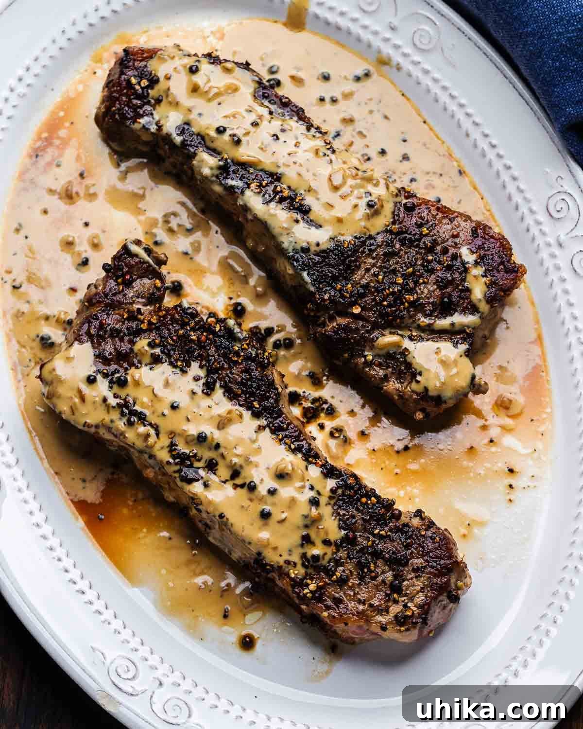 Pepper Crusted Steak 2 Steak au poivre in white platter with blue napkin.