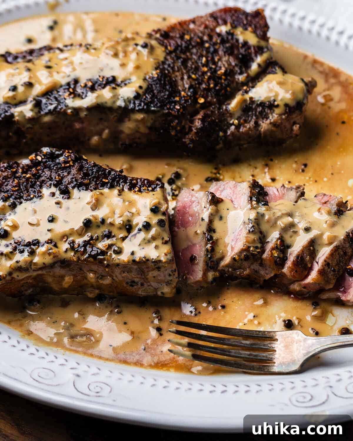 Pepper Crusted Steak 9 Sliced New York strip steak au poivre in white plate.
