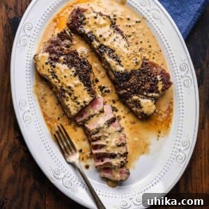 Steak au poivre in white platter white on table.
