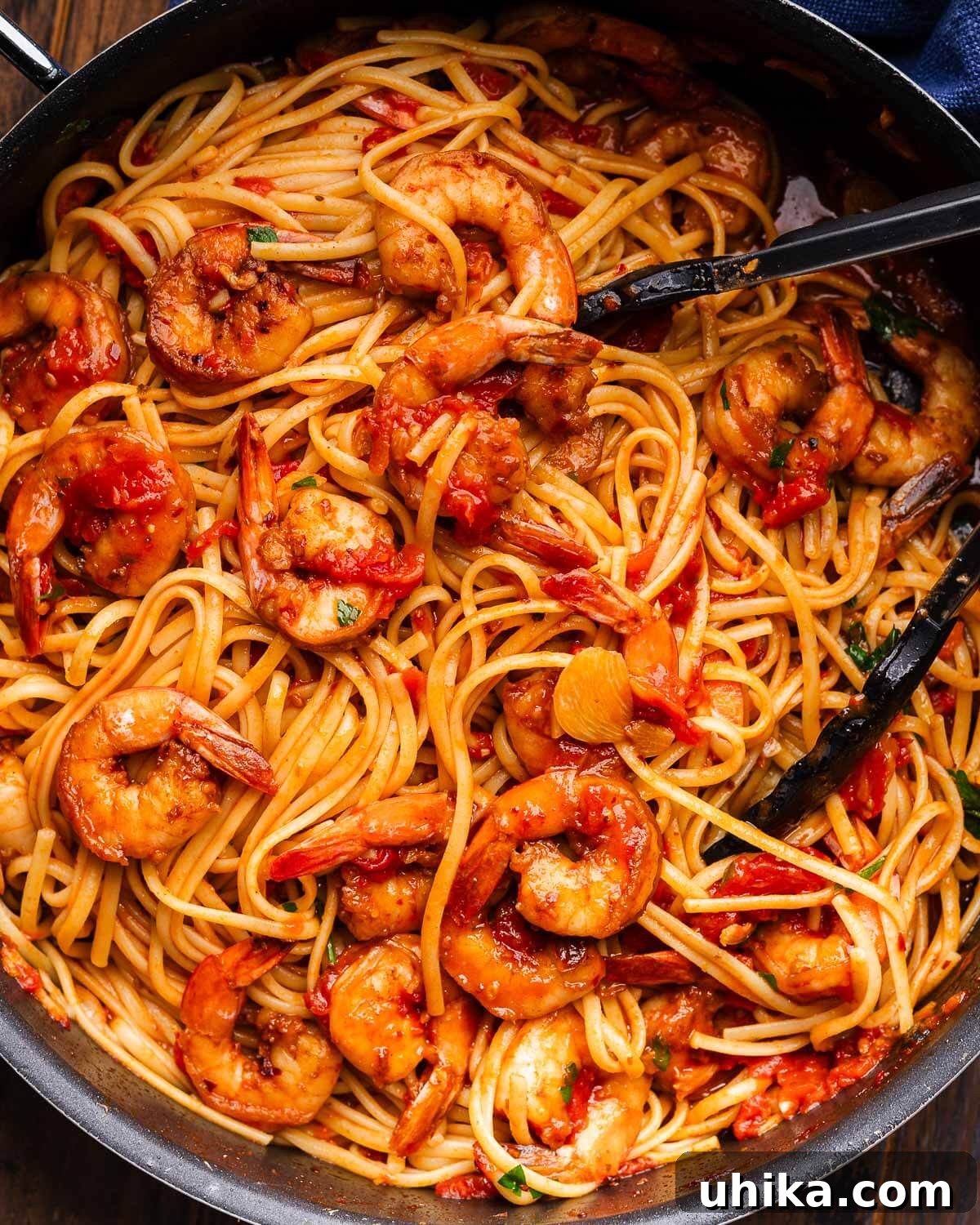 Fiery Fra Diavolo Shrimp Linguine 2 Close up photo of shrimp fra diavolo in black pan with tongs.