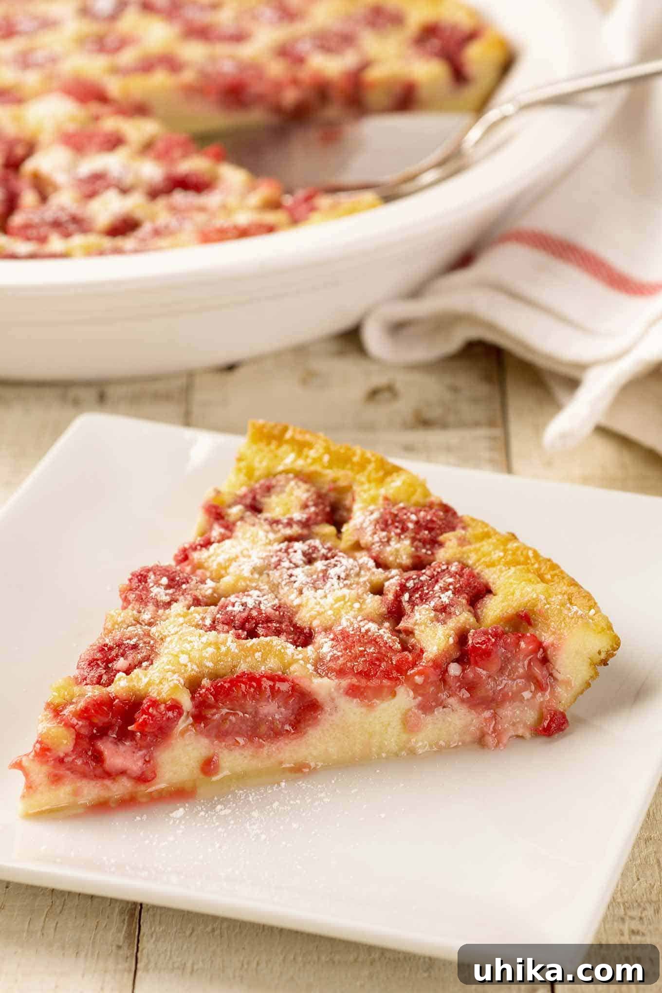 Berry-Kissed Custard Delight 3 A close view of a wedge of raspberry clafoutis on a plate showing the delicate, custardy texture of the clafoutis and juiciness of the raspberries, inviting a bite.