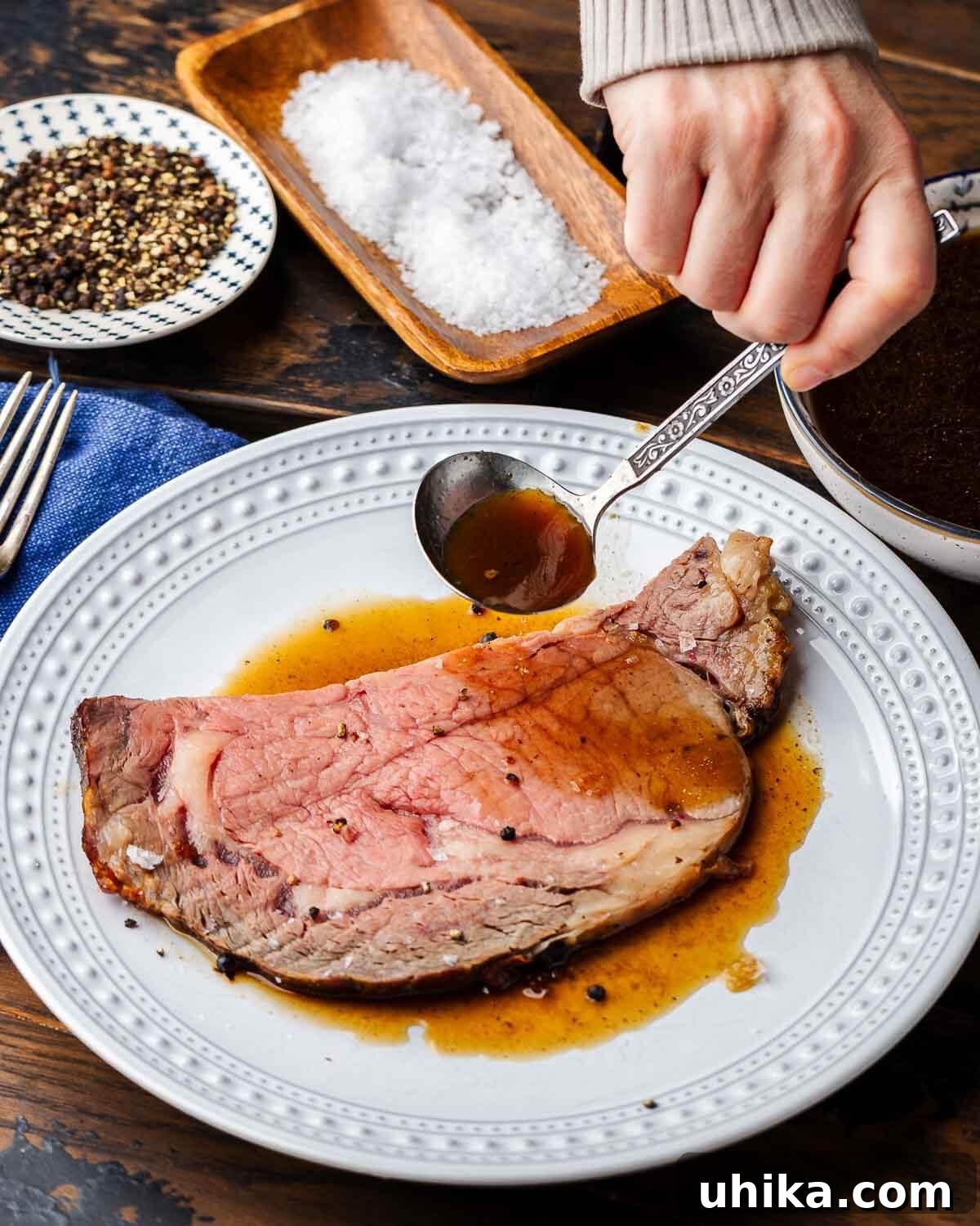 Podcast 29: Christmas Traditions - Comfort, Chaos, and Everything In Between 2 Hands ladling au jus onto slice of prime rib.