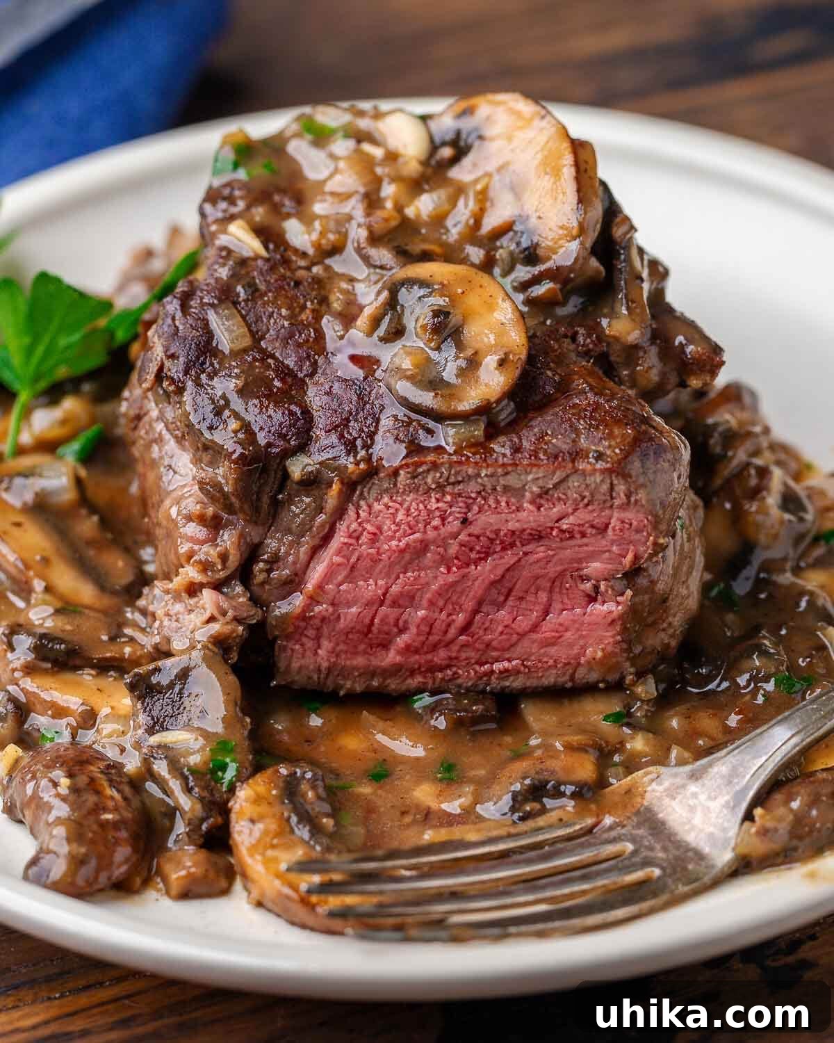 Rich Marsala-Braised Beef 2 A perfectly cooked filet mignon, sliced to reveal its tender interior, generously coated with a rich, dark mushroom Marsala sauce.