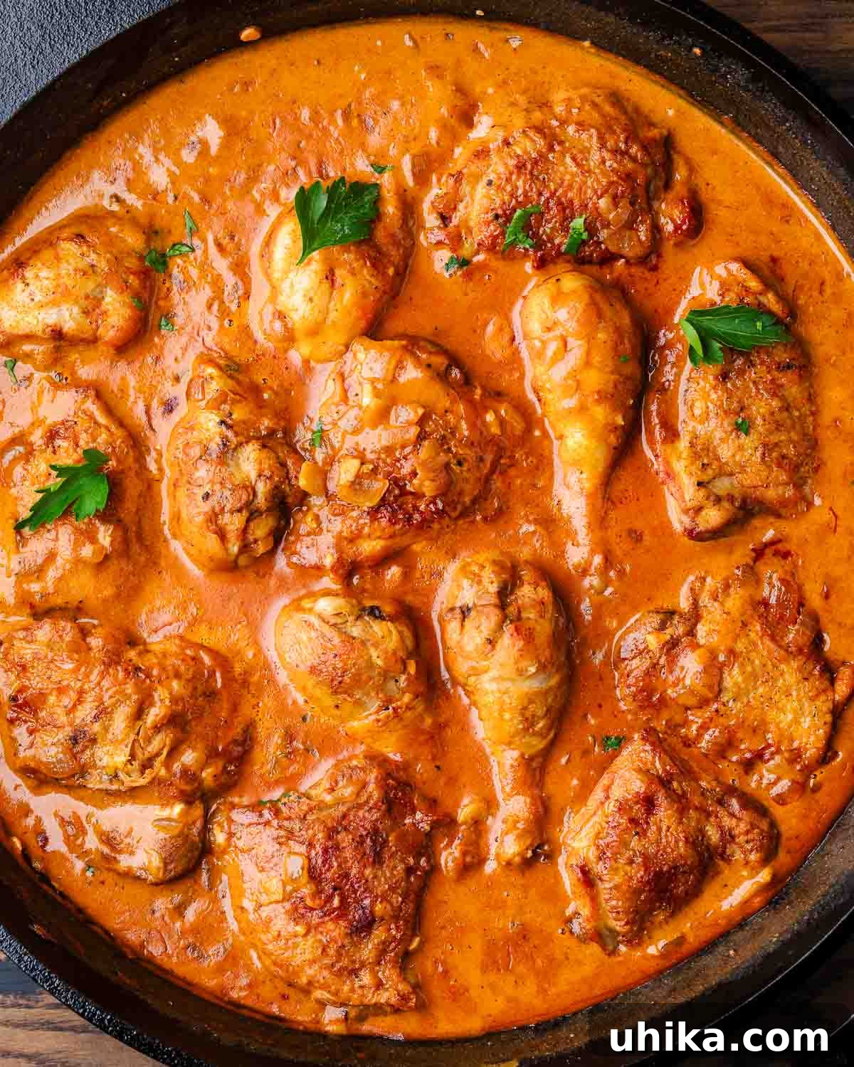 Hearty Paprikash Chicken with Cloud-Like Dumplings 2 Chicken paprikash in cast iron pan with parsley garnish.