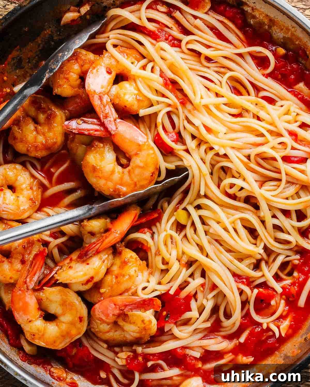 Podcast 32: The Unforgettable Power of Food Memories 3 Vibrantly red Shrimp Fra Diavolo bubbling intensely in a stainless steel pan, with a pair of kitchen tongs poised, ready to serve. The dish exudes warmth and a spicy allure, capturing the essence of a comforting and exciting Italian meal.