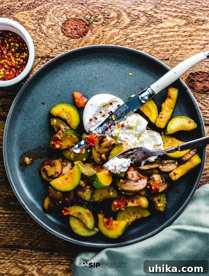 Sauteed Zucchini and Mushrooms with Burrata - Easy Italian Side Dish A beautifully plated dish of sauteed zucchini and mushrooms topped with creamy burrata cheese, viewed from overhead.