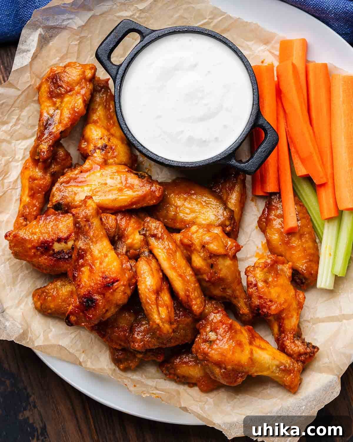 Buffalo Wing Perfection 2 Platter of golden brown, saucy buffalo wings served with cool blue cheese dressing, crisp celery sticks, and vibrant carrot sticks.