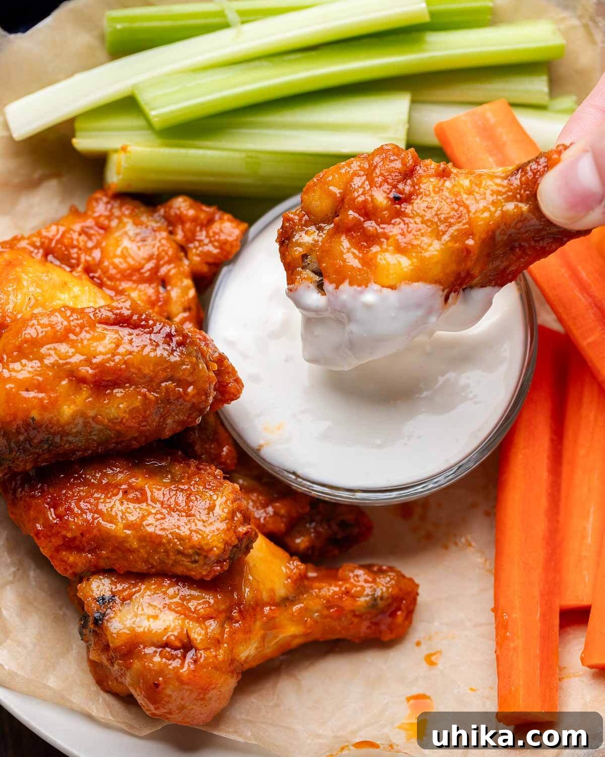 Buffalo Wing Perfection 8 Close-up of a hand dipping a crispy buffalo wing into creamy blue cheese dressing.