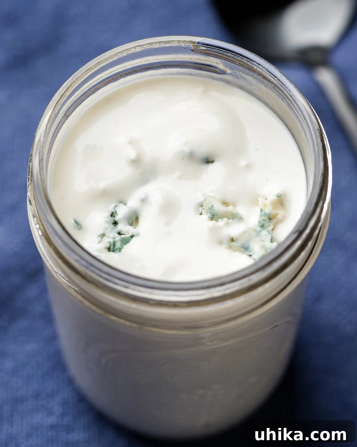 Freshly made blue cheese dressing in a clear mason jar, resting on a blue linen napkin, ready to be served.