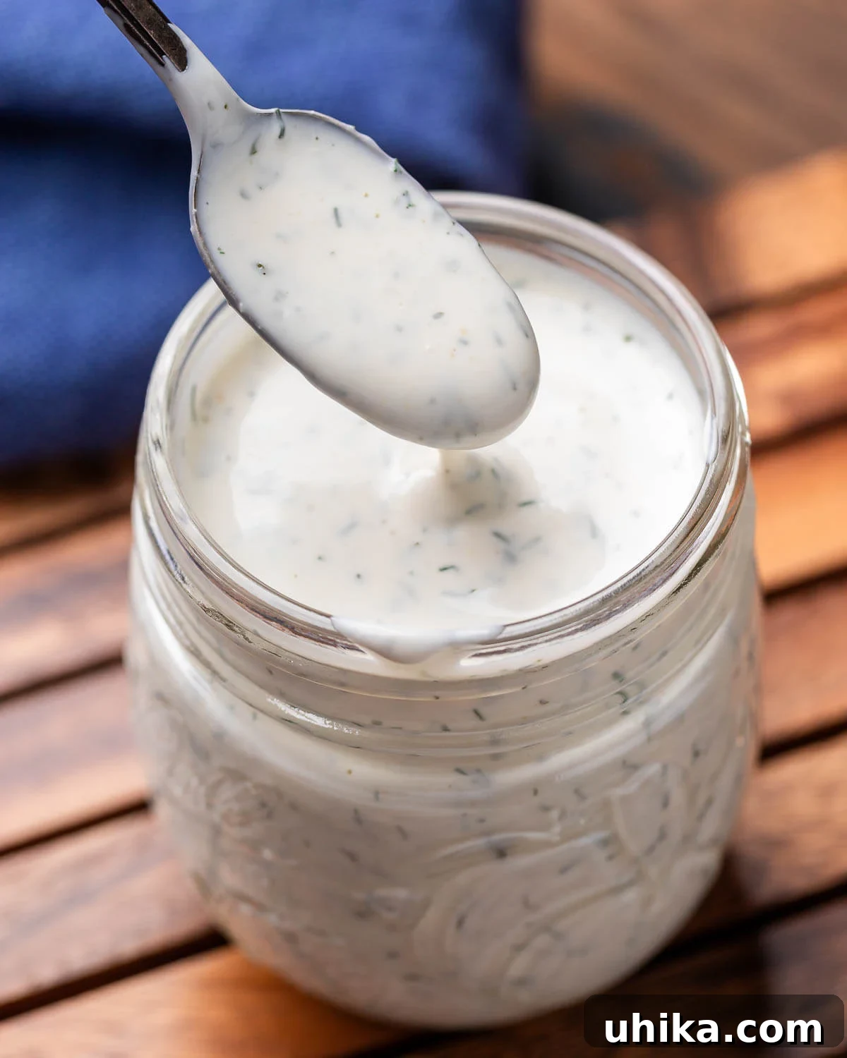 Velvet Buttermilk Ranch 2 Spoon drizzling creamy homemade ranch dressing into a clear glass jar.