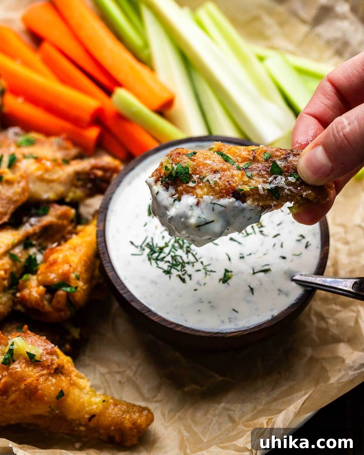 Velvet Buttermilk Ranch 5 Hands dipping a crispy chicken wing into a bowl of creamy buttermilk ranch dressing.