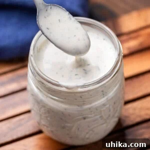Jar of buttermilk ranch dressing with a spoon resting inside.