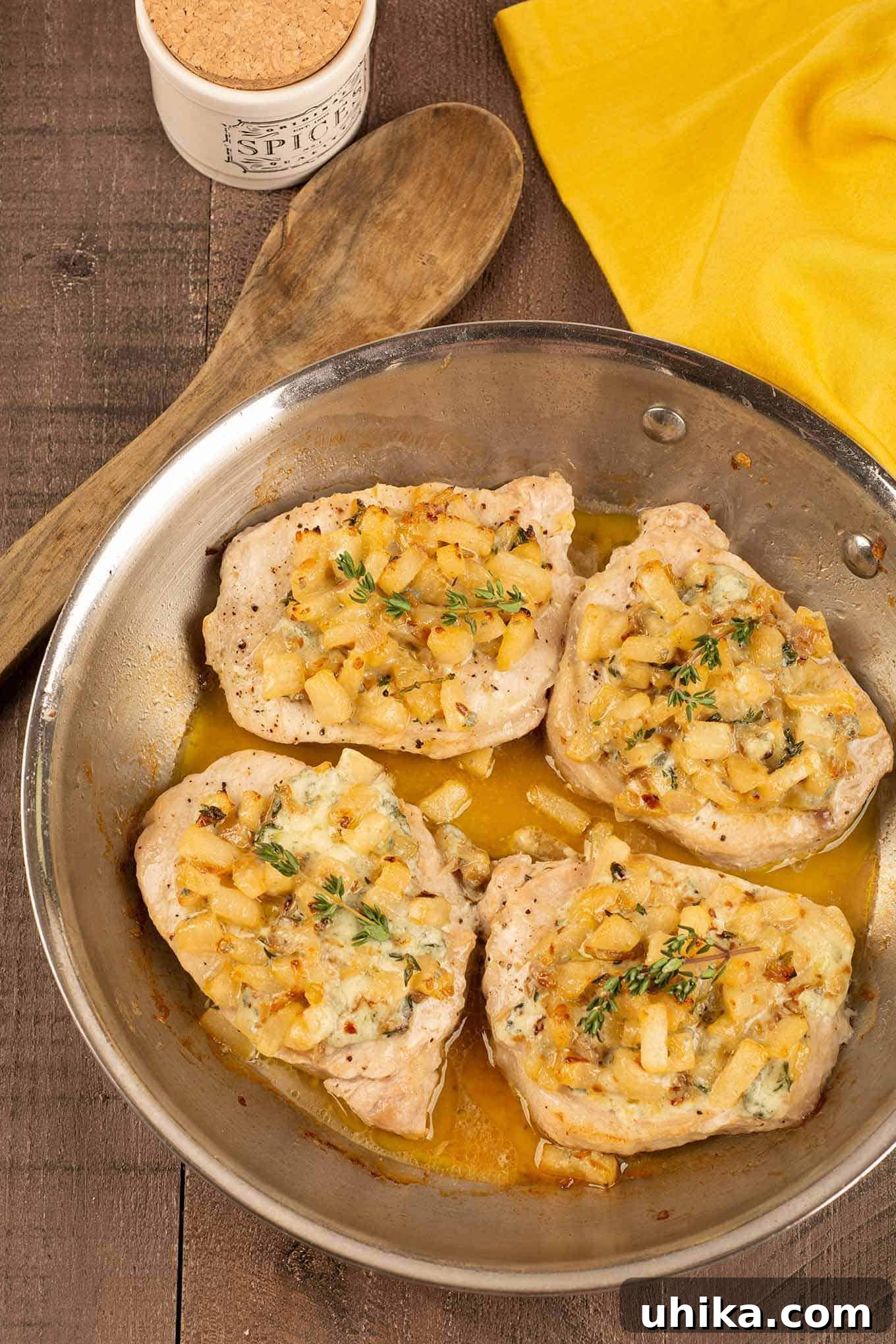 Pan-Seared Pork Chops with Caramelized Pears 3 A frying pan with four boneless pork chops in a light pan sauce, topped with pears, blue cheese, and sprigs of thyme.