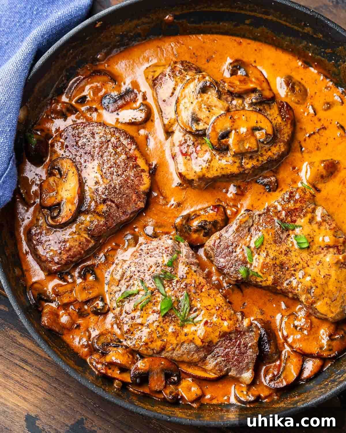 Vintage Flambéed Steak Diane 2 A perfectly seared Steak Diane in a black pan, generously coated with a rich, creamy mushroom and cognac sauce, ready to be served.