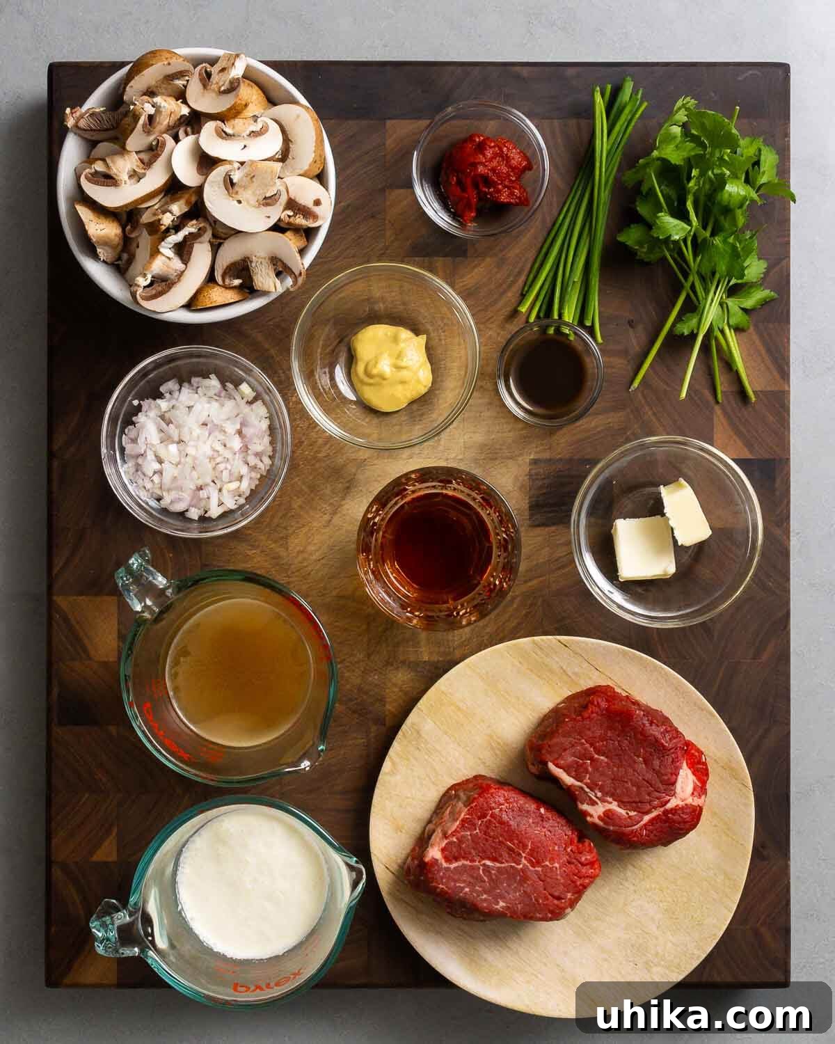 Vintage Flambéed Steak Diane 3 A spread of fresh ingredients for Steak Diane, including cremini mushrooms, tomato paste, chives, parsley, a shallot, Dijon mustard, brandy, butter, Worcestershire sauce, beef stock, heavy cream, and choice cuts of beef tenderloin.