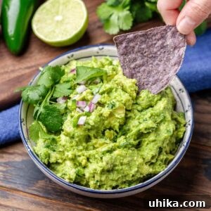 Guacamole Perfection 8 Blue corn chip dipped into bowl of guacamole for featured image.
