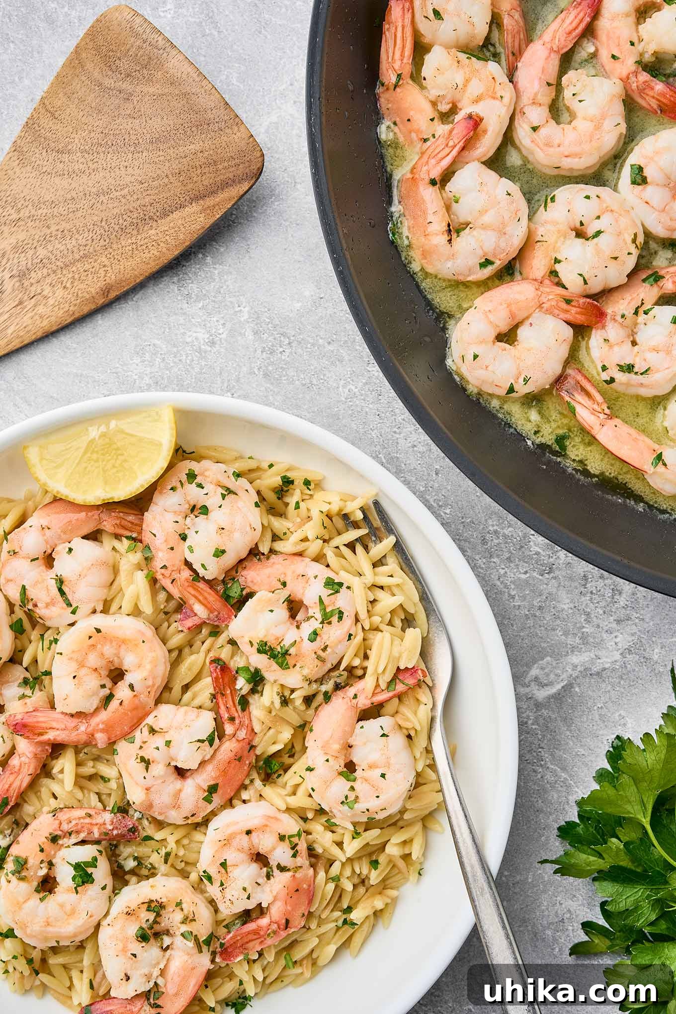 Garlic butter shrimp scampi cooking in a pan with a plated bowl of shrimp and orzo pasta garnished with herbs and a lemon wedge.