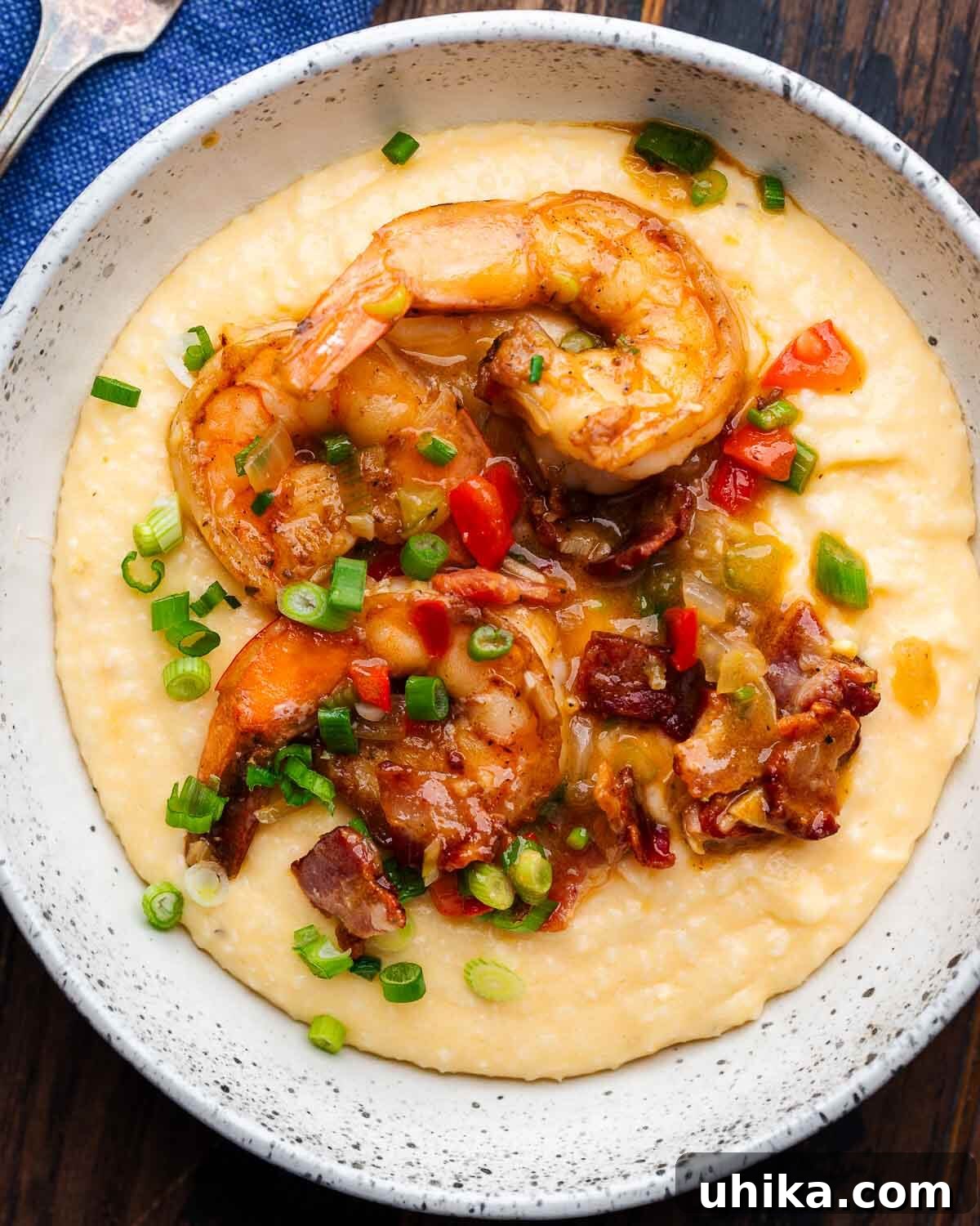 Southern Comfort Shrimp and Grits 2 A beautiful white bowl overflowing with creamy shrimp and grits, garnished with crispy bacon bits and fresh green onions.