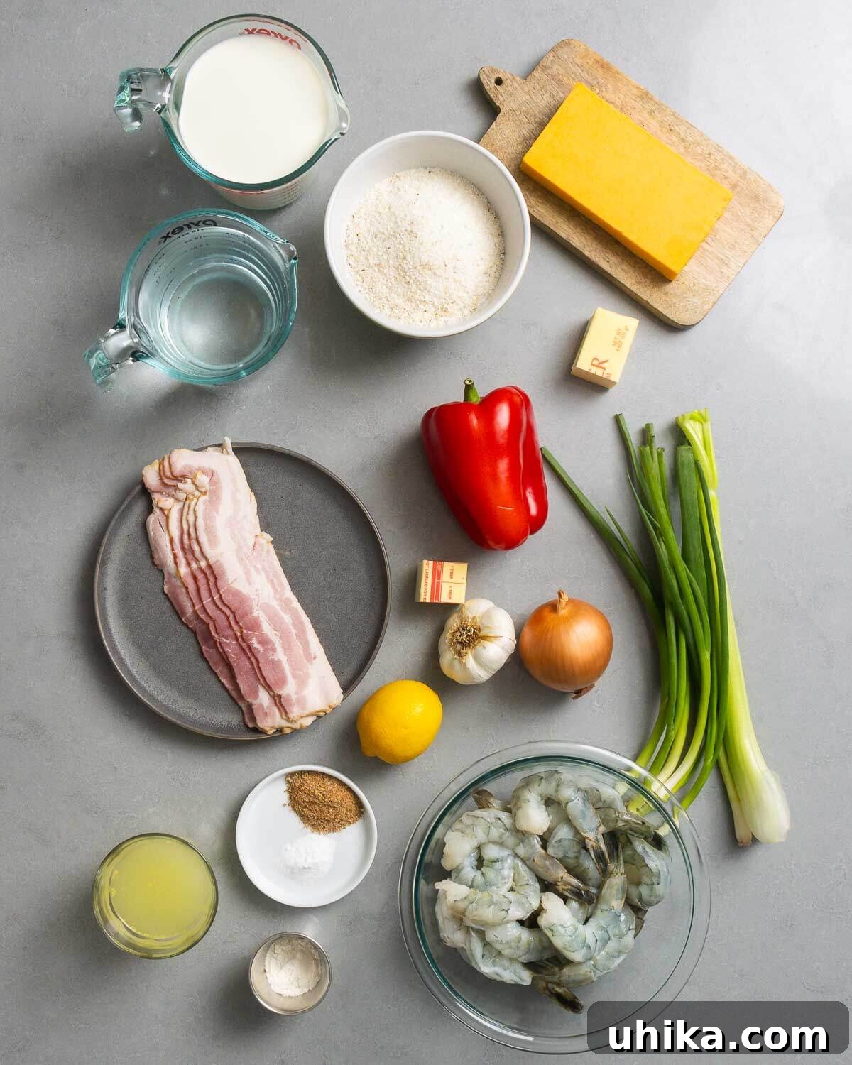 Southern Comfort Shrimp and Grits 3 A flat lay photograph showcasing all the fresh ingredients for Shrimp and Grits: milk, water, white grits, sharp cheddar cheese, butter, smoked bacon, red bell pepper, minced garlic, a yellow onion, fresh green onions, crisp celery, low-sodium chicken stock, a selection of spices including Cajun seasoning, a bright lemon, and plump, raw shrimp.