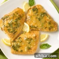 Golden Oven-Crisped Fish with Lemon Basil Butter 4 Three pieces of breaded, oven-fried fish fillets topped with lemon butter infused with fresh basil and garnished with basil leaves and lemon wedges.