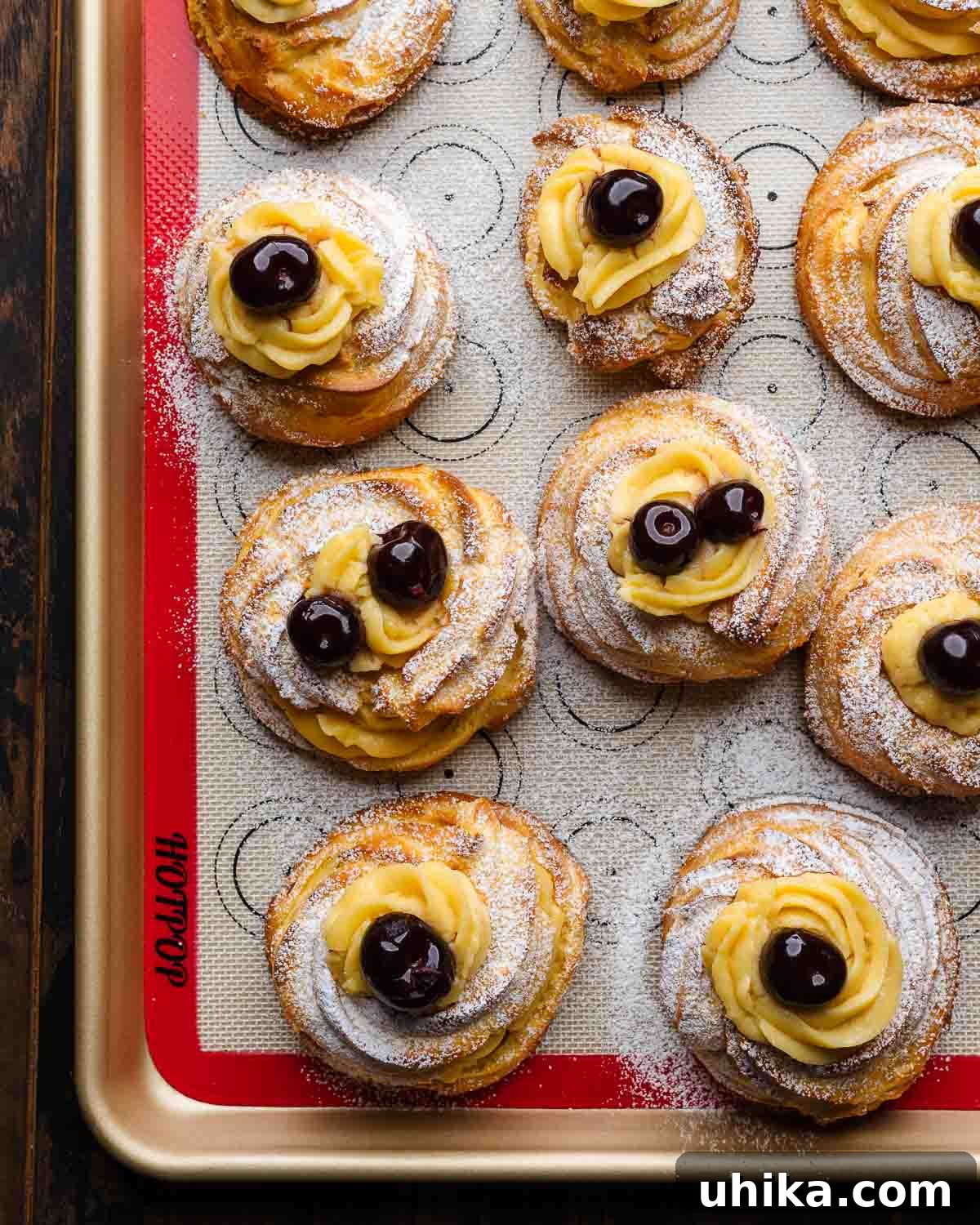 St. Joseph's Day Zeppole 12 A close-up view of beautifully baked St. Joseph's Day Pastries, or Zeppole, cooling on a silicone-lined baking sheet, showcasing their perfect golden color and puffed form before filling.