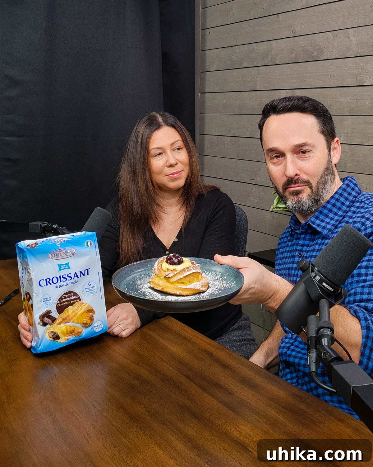 Five-Star Feasts on a Shoestring Budget Taste Tested 3 Jim holding plate with Italian pastry and Tara holding pack of Italian Croissants, preparing for a taste test.