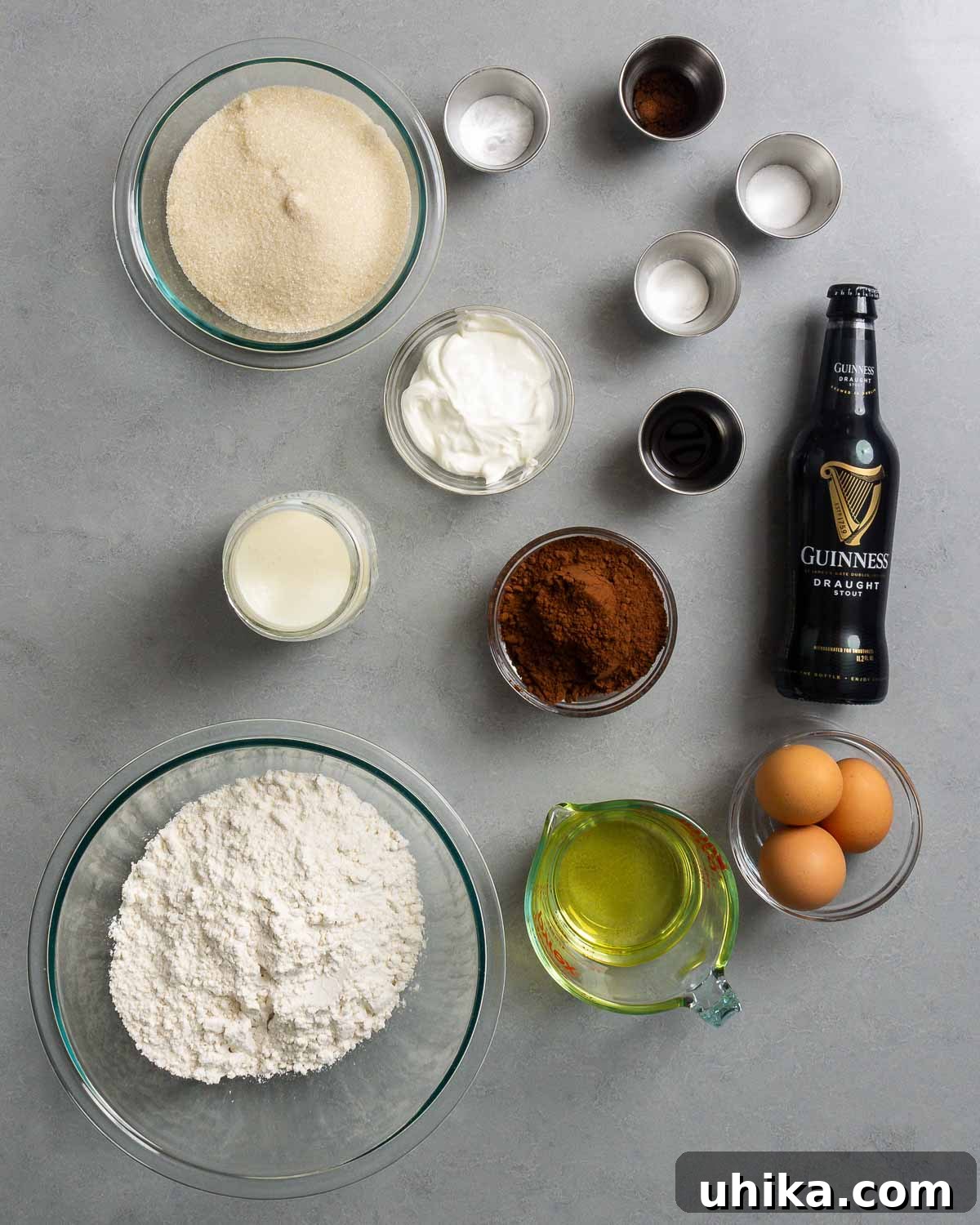 Velvet Guinness Chocolate Cake with Baileys Irish Cream Frosting 3 All the dry and wet ingredients laid out on a table, including sugar, sour cream, salt, baking powder, baking soda, espresso powder, vanilla extract, cocoa powder, Guinness stout, buttermilk, eggs, vegetable oil, and all-purpose flour.