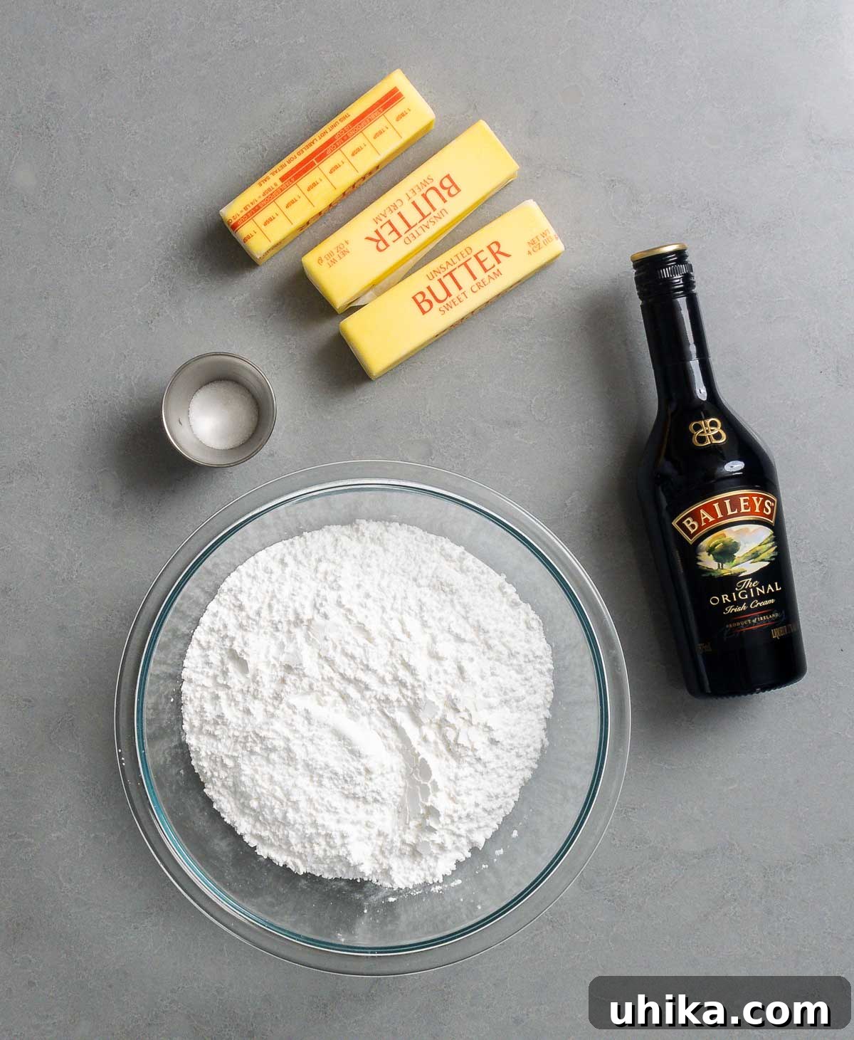 Velvet Guinness Chocolate Cake with Baileys Irish Cream Frosting 4 Ingredients for Baileys Buttercream Frosting displayed: softened unsalted butter, a bag of confectioner's sugar, a bottle of Baileys Irish Cream, and a small dish of salt.