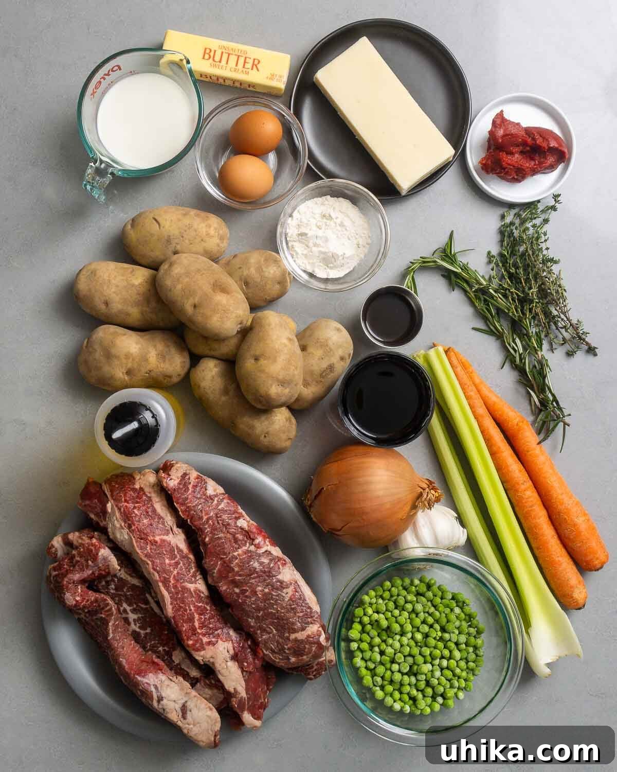 Slow-Braised Short Rib Cottage Pie 3 A vibrant display of all fresh and pantry ingredients for cottage pie: milk, butter, eggs, cheddar, tomato paste, flour, Worcestershire sauce, fresh herbs (rosemary, thyme), russet potatoes, red wine, olive oil, celery, carrots, garlic, onion, peas, and boneless short ribs.