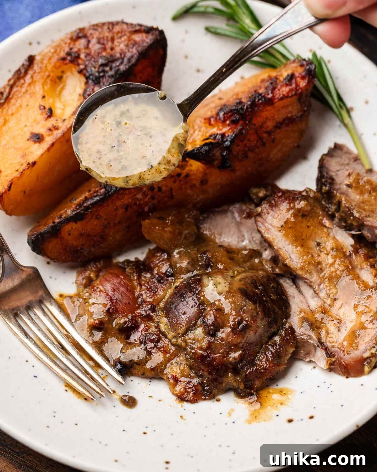 Succulent Greek Slow-Roasted Lamb Leg with Lemon-Herb Potatoes 9 White plate showcasing a portion of Greek-style leg of lamb and golden potatoes, with a spoon drizzling vibrant ladolemono sauce over the top.