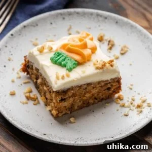 Carrot cake in white plate with sprinkled walnuts around the edges.