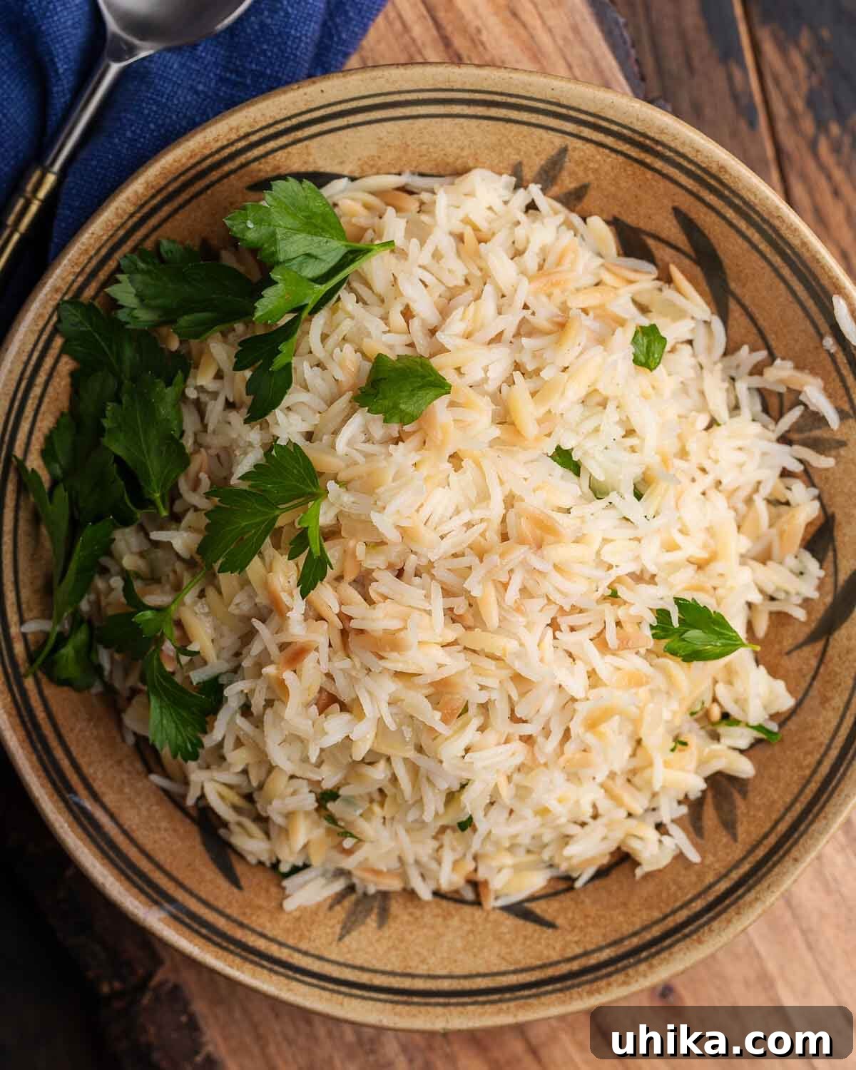 Aromatic Buttered Rice 7 Tahta bir tahta üzerinde turuncu bir kasede servis edilen pirinç pilavı.