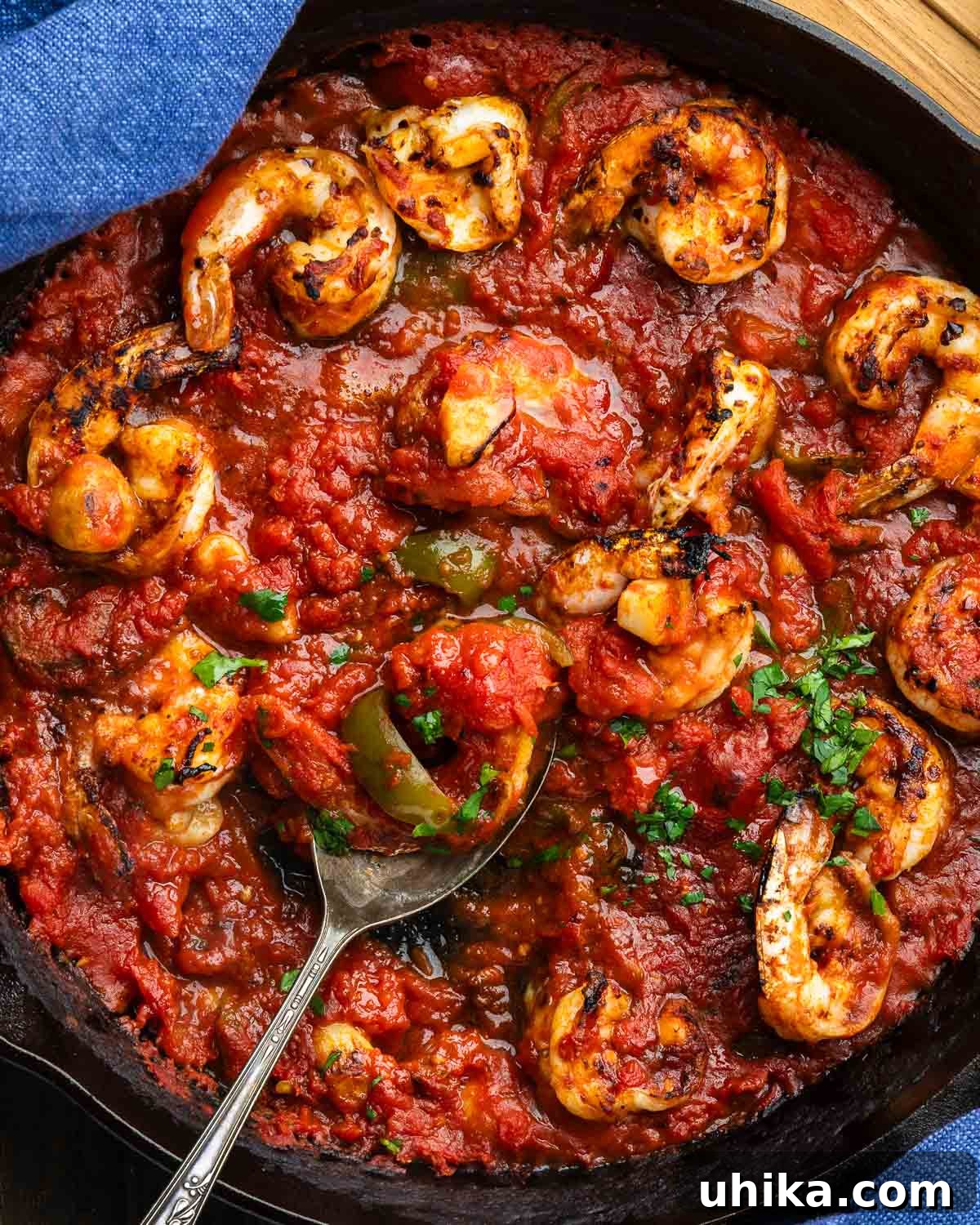 Spicy Scarlet Shrimp 7 Large pan with shrimp in spicy sauce with spoon holding shrimp.