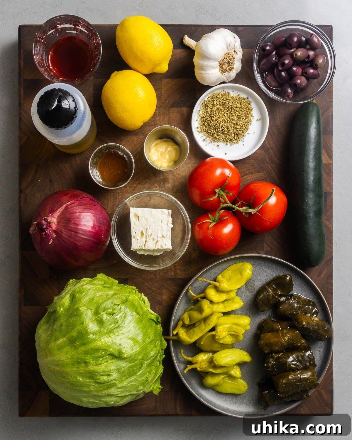 Classic New York Diner Greek Salad 3 Ingredients shown: red wine vinegar, lemons, olive oil, garlic, kalmata olives, oregano, honey, Dijon mustard, onion, feta cheese, tomatoes, cucumber, iceberg lettuce, Tuscan peppers, and stuffed grape leaves.