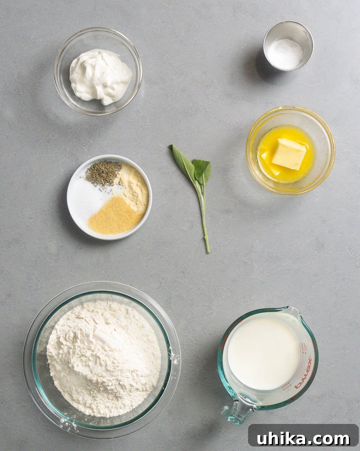 Hearty Homestyle Chicken and Dumplings 4 A collection of ingredients for homemade dumplings, including sour cream, baking powder, a mix of dried spices like sage and thyme, melted butter, cake flour, and fresh milk.