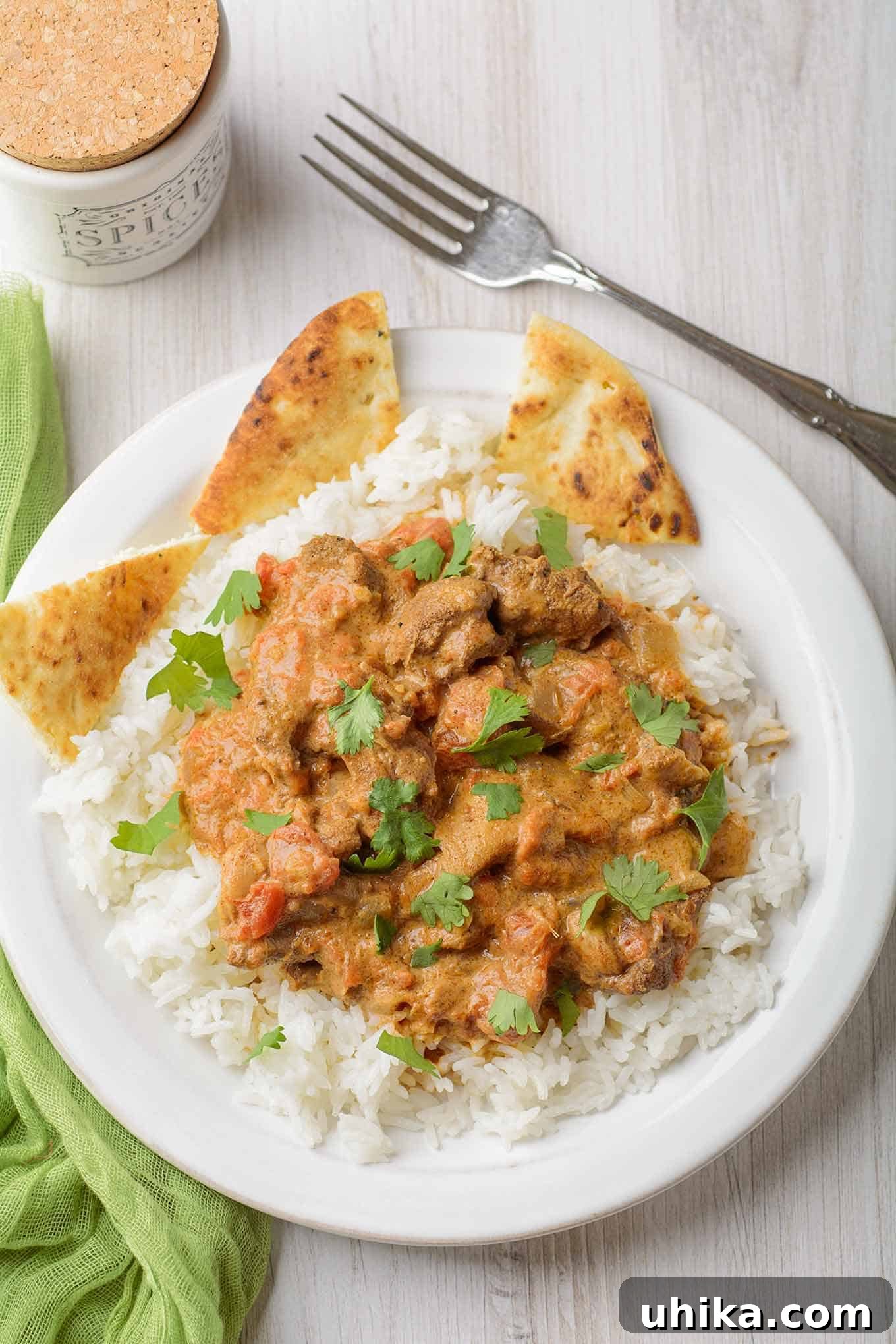 Effortlessly Delicious Instant Pot Chicken Tikka Masala 2 An overhead view of chunks of boneless chicken in a creamy, Indian-spiced tomato-based sauce served over rice and garnished with cilantro - pita on the side. A perfect Instant Pot Chicken Tikka Masala for a quick and flavorful dinner.