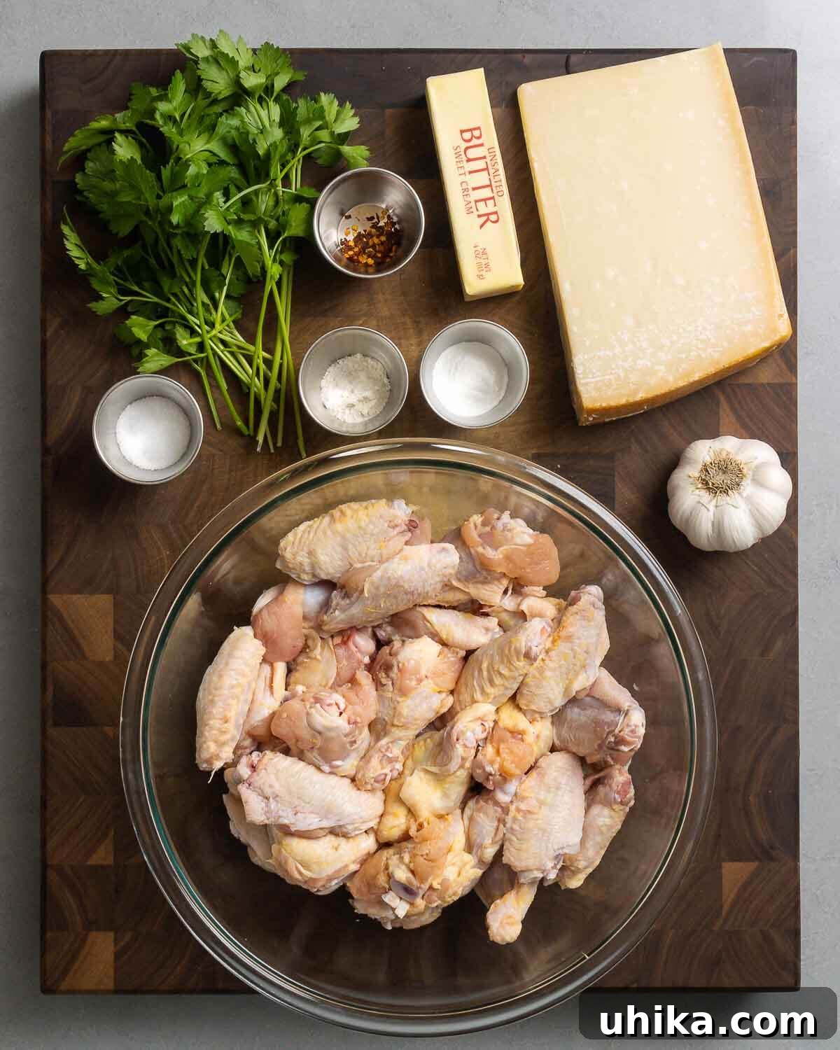 Irresistible Crispy Garlic Parmesan Wings 3 Collection of ingredients including fresh parsley, salt, flour, baking powder, butter, parmesan cheese, fresh garlic, and party chicken wings.