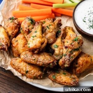 Garlic parmesan chicken wings in white plate with carrots and celery.