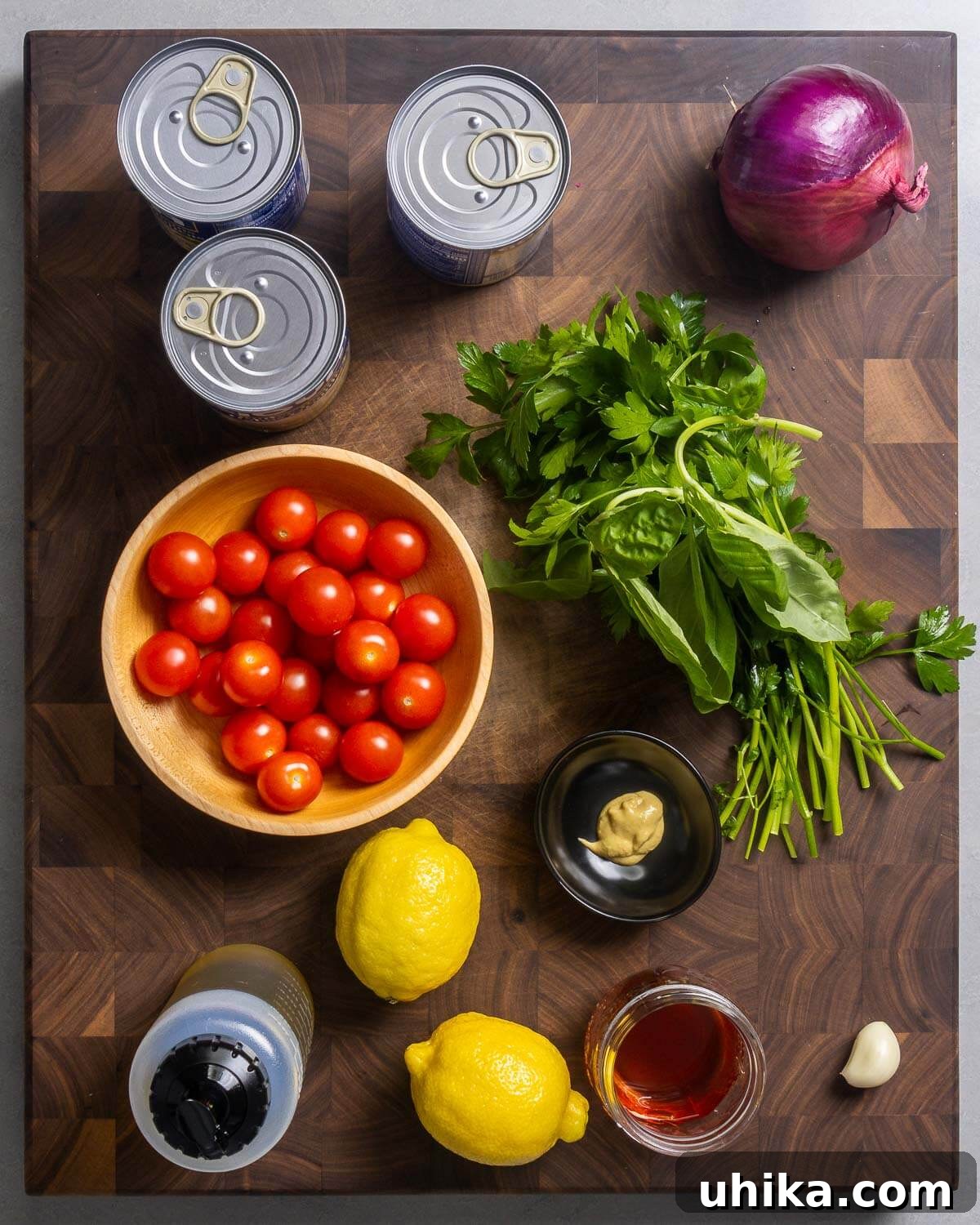 Rustic Italian White Bean Salad 3 A flat lay of all ingredients for Italian white bean salad: 3 cans of white beans, a red onion, cherry tomatoes, fresh parsley and basil, lemons, Dijon mustard, olive oil, red wine vinegar, and a clove of garlic.