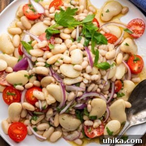 Italian white bean salad piled high on white platter, ready to be served at a summer gathering.