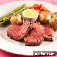 Châteaubriand steak served medium rare, accompanied by Sauce Béarnaise, roasted baby potatoes, roasted asparagus, and cherry tomatoes.