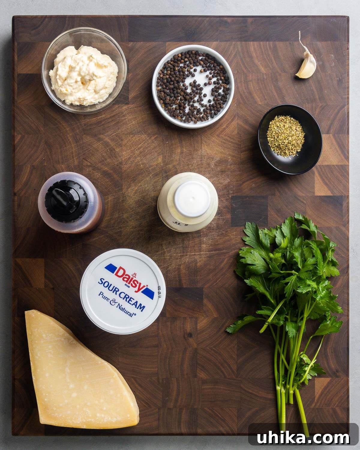 Velvety Parmesan Peppercorn Dressing 3 Ingredients shown: mayonnaise, peppercorns, garlic, oregano, red wine vinegar, buttermilk, sour cream, Parmigiano Reggiano cheese, and parsley.
