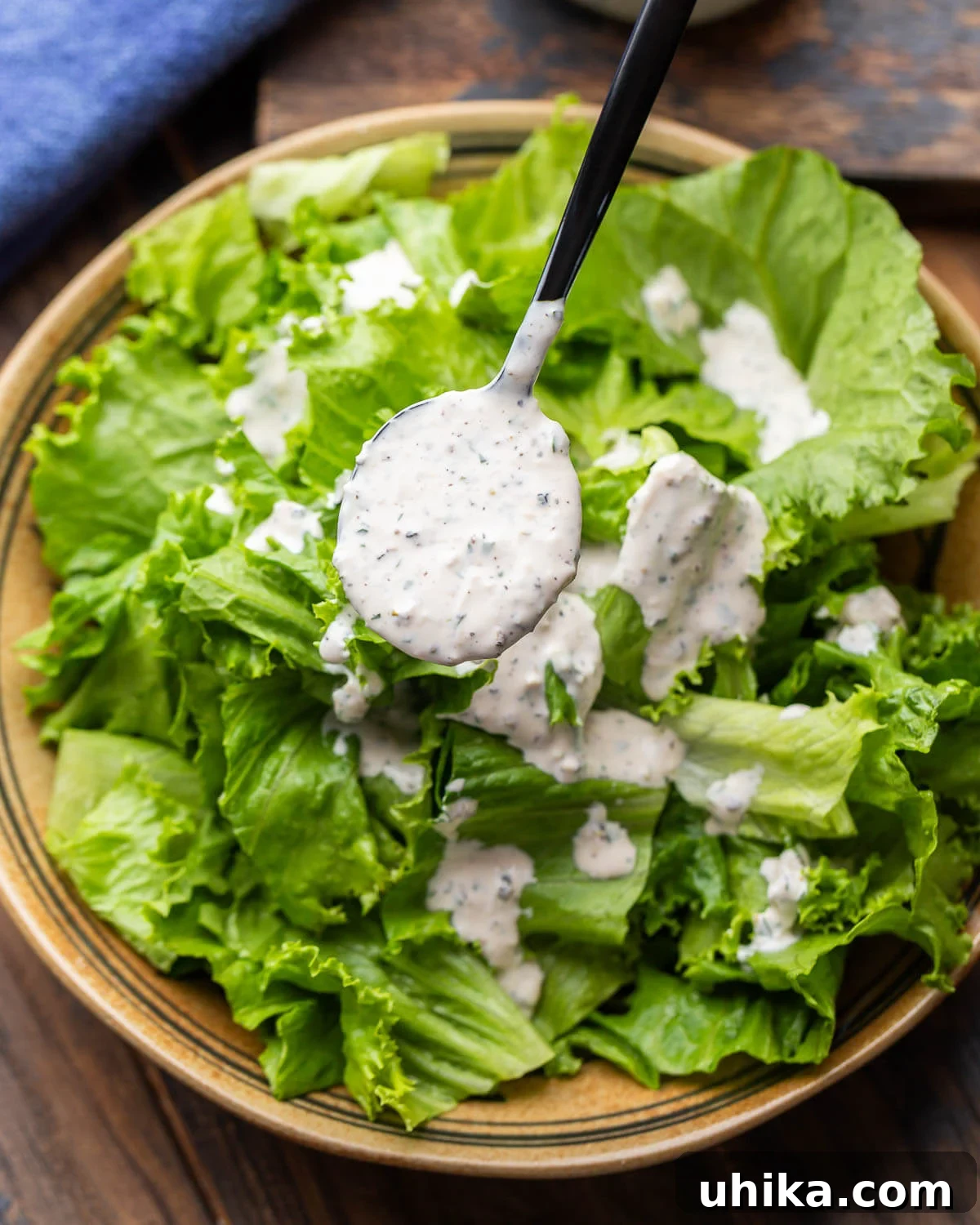 Velvety Parmesan Peppercorn Dressing 4 Creamy parmesan peppercorn dressing spooned over a bowl of salad.