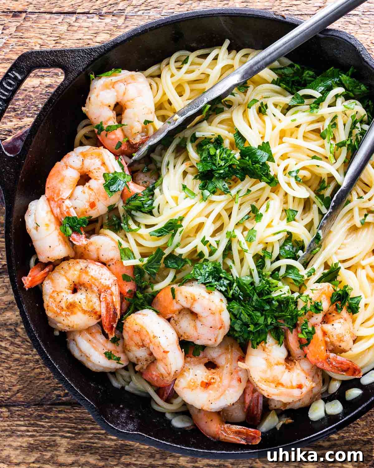 Vibrant Lemon Garlic Shrimp Pasta 3 Lemon garlic shrimp pasta in black pan with tongs.