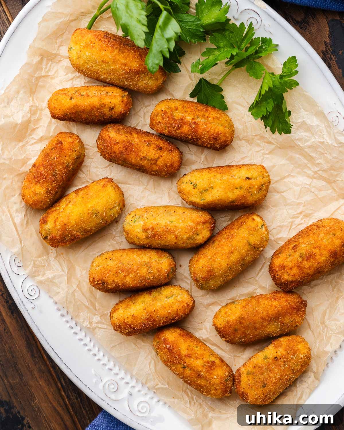 Crispy Italian Potato Bites 2 Golden brown Italian potato croquettes served on parchment paper, ready to be enjoyed.