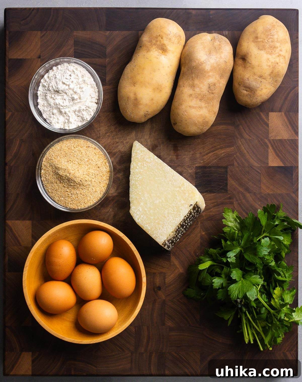 Crispy Italian Potato Bites 3 A selection of fresh ingredients laid out for Italian potato croquettes: flour, Russet potatoes, breadcrumbs, Pecorino Romano cheese, eggs, and fresh parsley.
