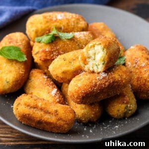 Plate of Italian potato croquettes with one cut in half, showcasing the fluffy interior.