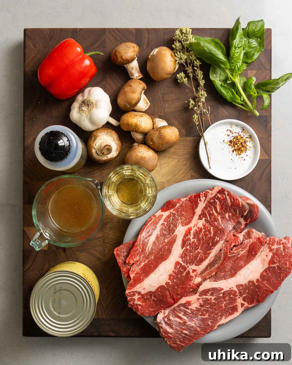 Classic Steak Pizzaiola 4 Ingredients shown: chuck steaks, red bell pepper, mushrooms, oregano, basil, garlic, olive oil, beef stock, white wine, red pepper flakes, and plum tomatoes.
