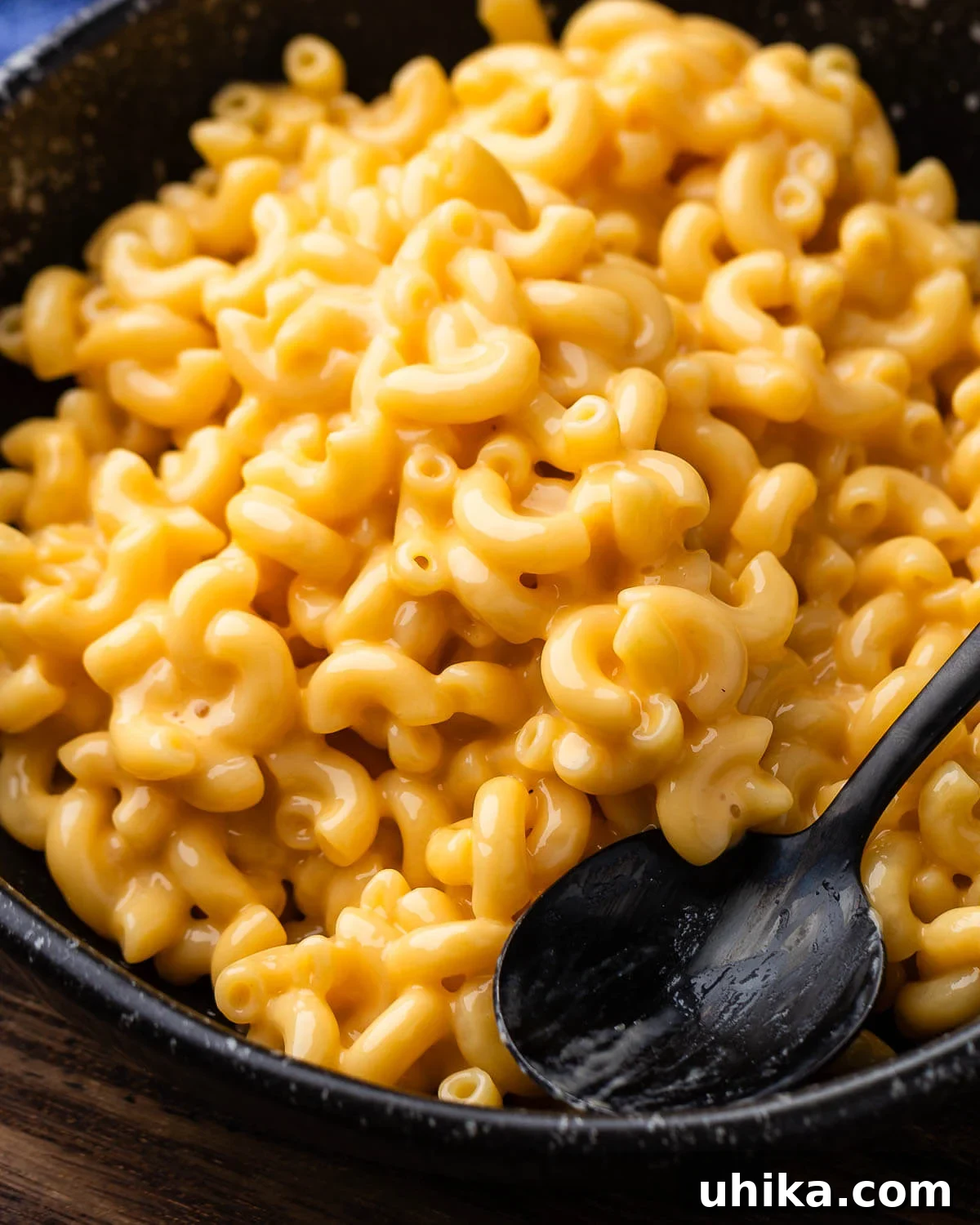 Stovetop mac and cheese served in a rustic black bowl with a spoon, ready to be enjoyed.